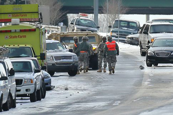 Georgia National Guard troops and a HERO unit search abandoned vehicles to give aid to those still stuck on a highway in Atlanta. Photo from ajc.com
